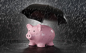 A pink piggy bank under an umbrella in the rain.
